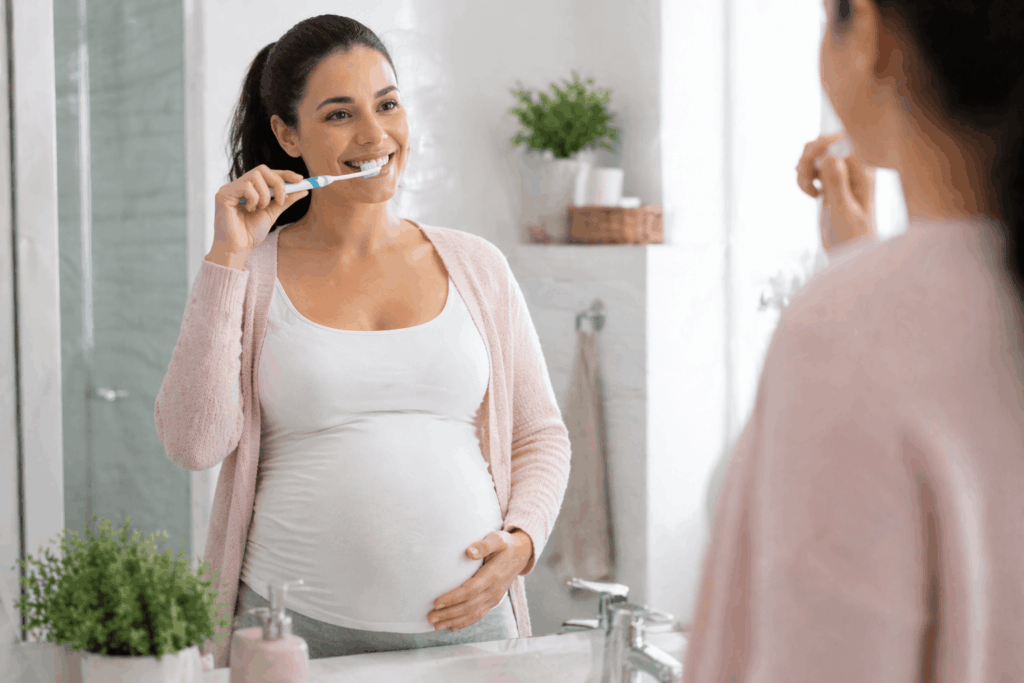 Pregnant woman brushing teeth in bathroom maintaining daily oral hygiene routine